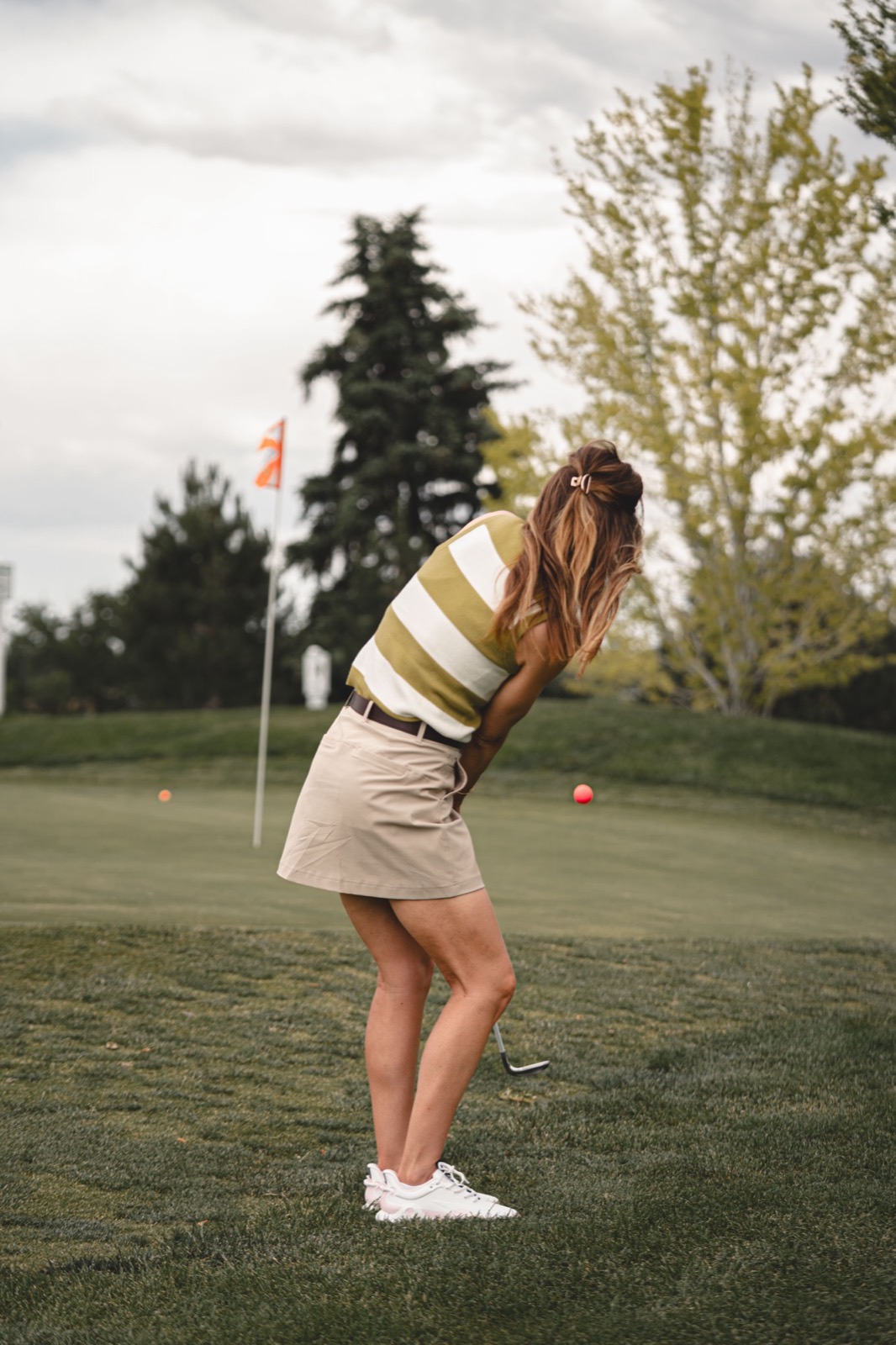A woman on the fairway with a club over her shoulder, looking down the course