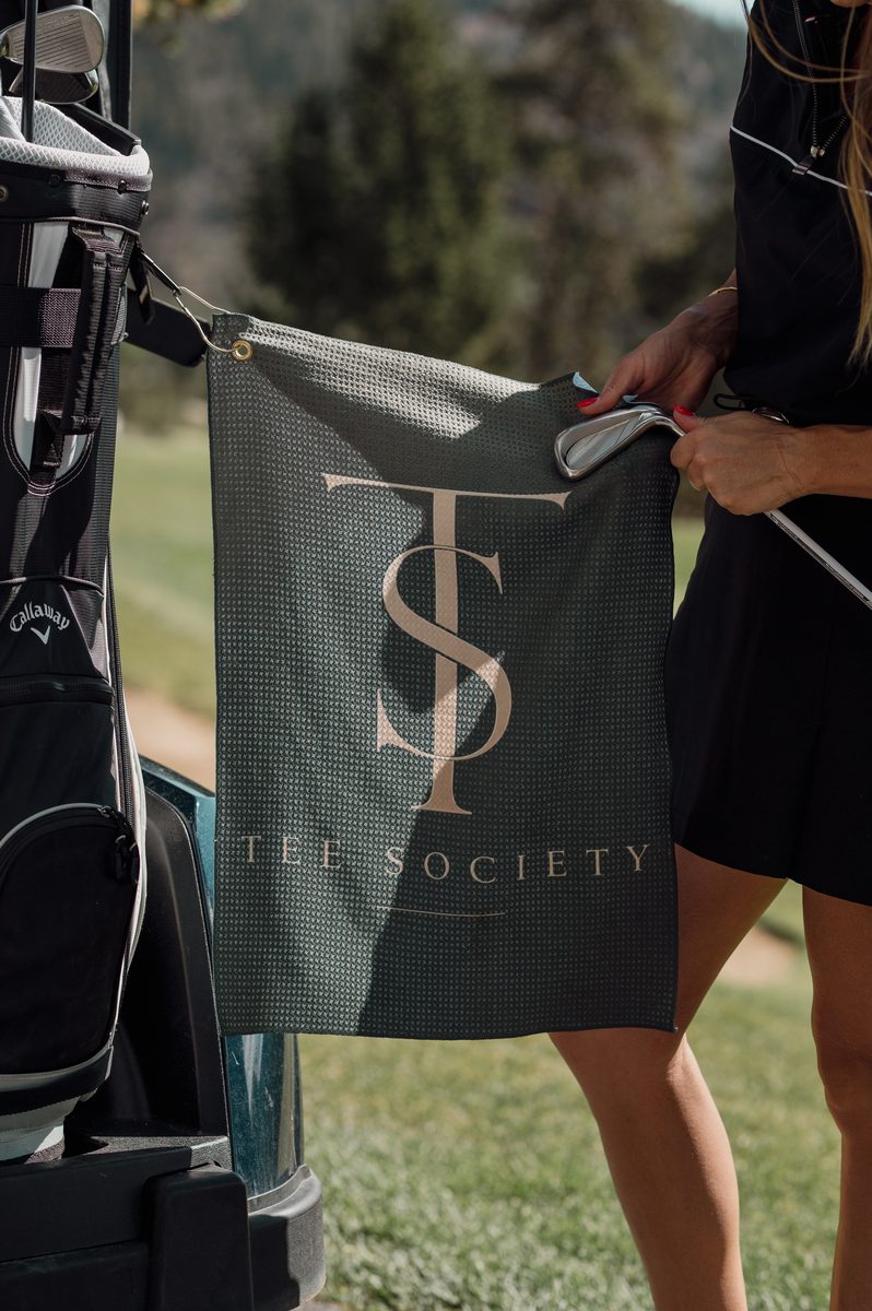 A Tee Society towel hanging from a golf bag