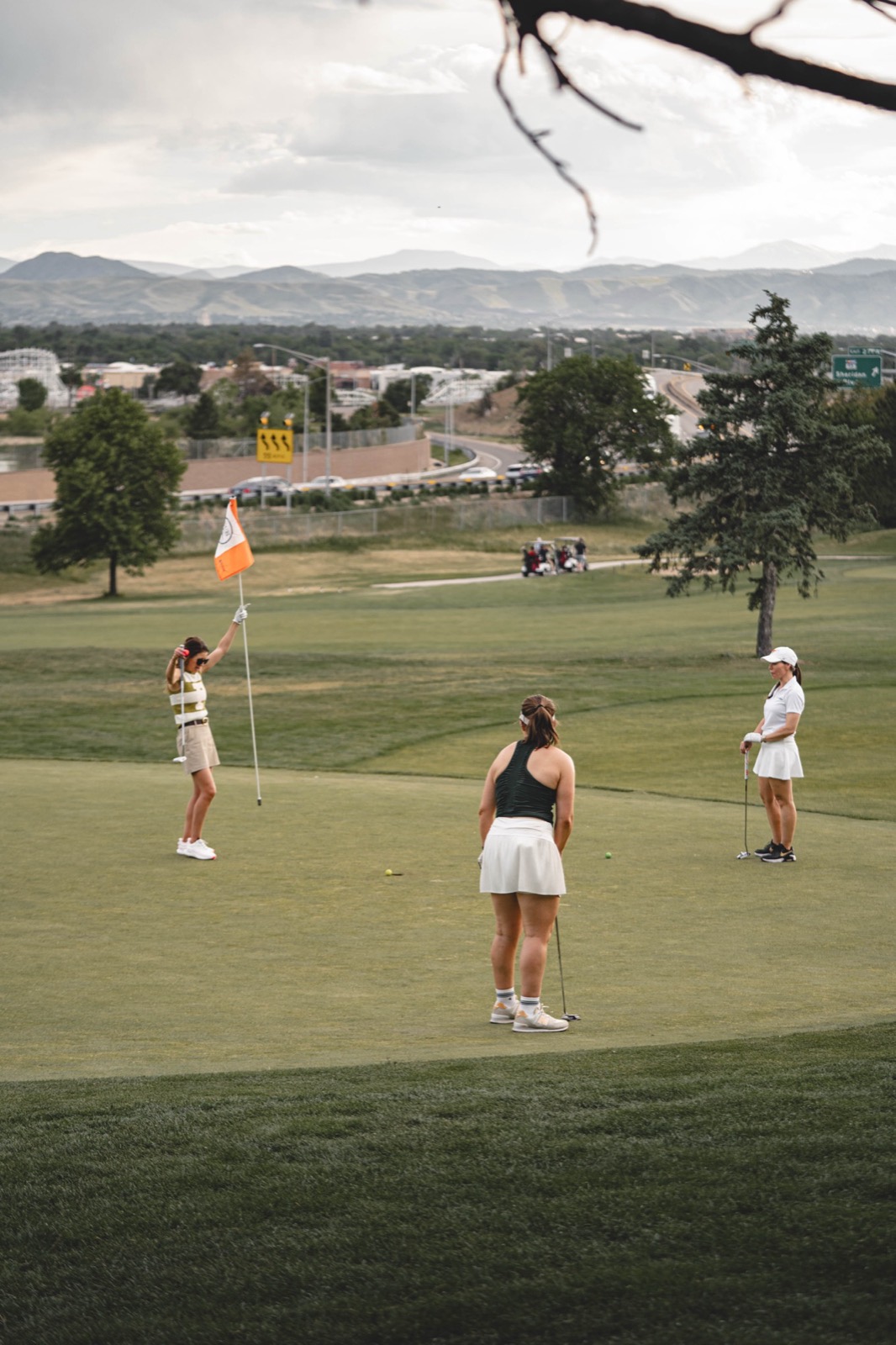 Golfers on the green with the Rocky Mountains stretching across the horizon